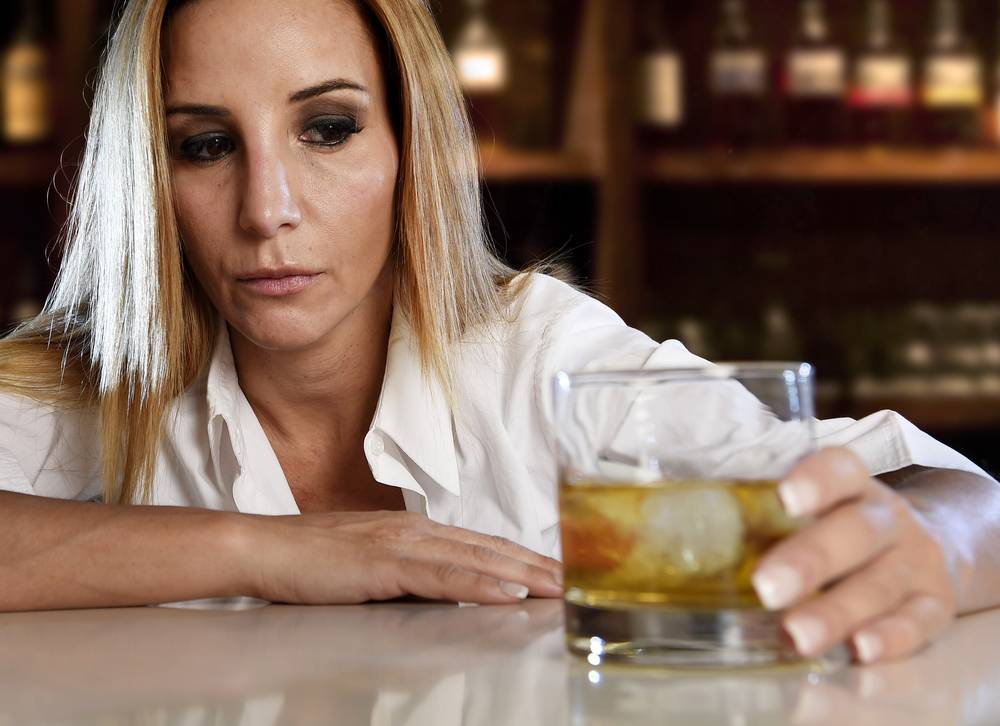 mulher com copo de whisky no balcão do bar