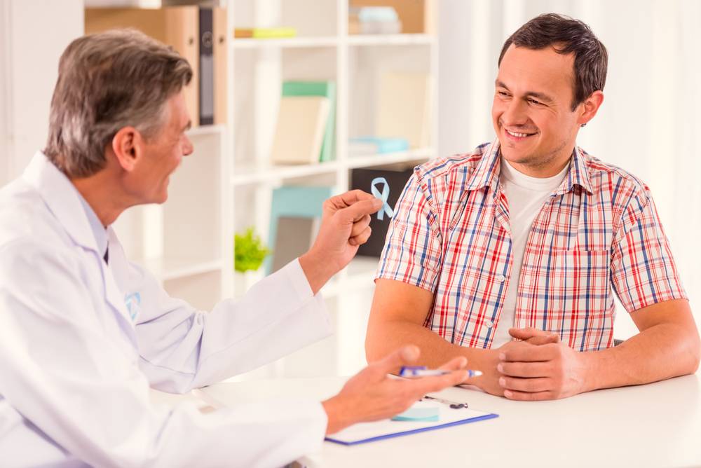 médico entregando o simbolo do novembro azul para paciente homem com camisa xadrez