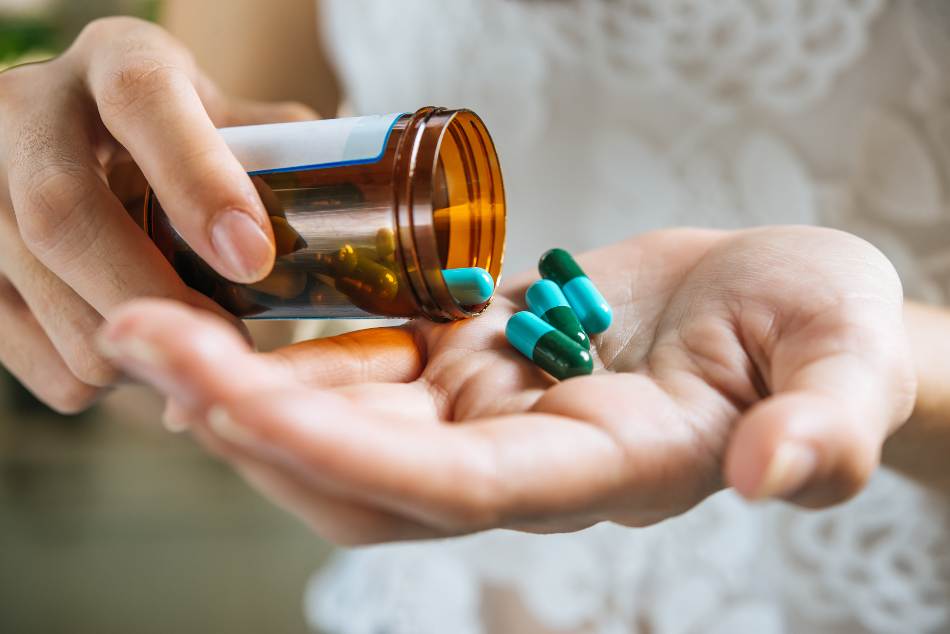 vidro de remedio derramando opioides em mão feminina
